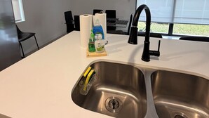 A modern kitchen with a double sink, a black faucet, and a window with a view of a building. - Spacious 4-bedroom house in wonderful Florida City with AC (Florida City)