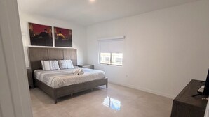 A bedroom with a bed, a nightstand, a dresser, and a window with blinds. - Spacious 4-bedroom house in wonderful Florida City with AC (Florida City)