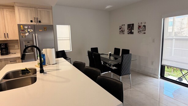 A modern kitchen with a central island, a dining area with black chairs, and a large window. - Spacious 4-bedroom house in wonderful Florida City with AC (Florida City)