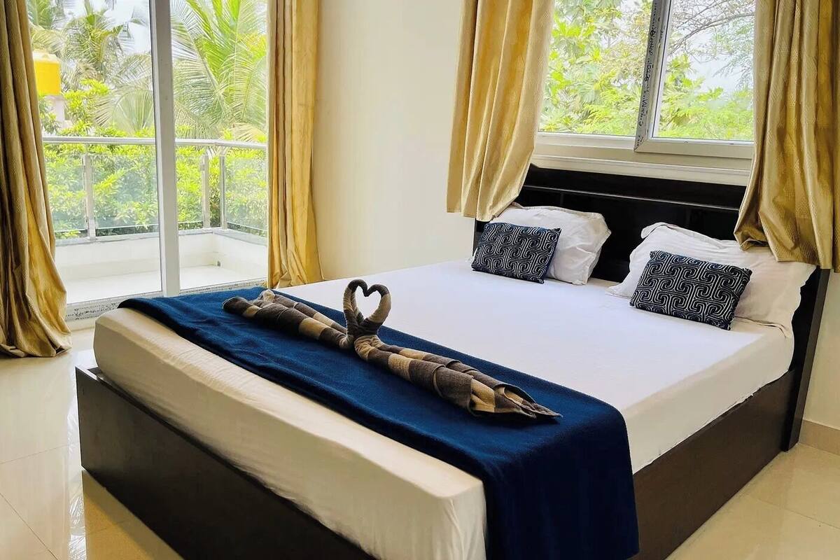 Ein Hotelzimmer mit einem großen Bett, Blick ins Grüne und einem Balkon.