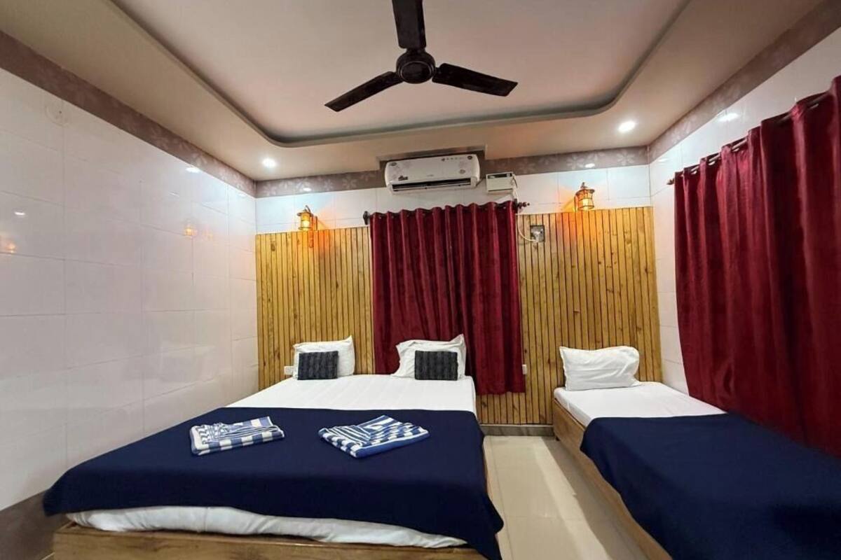Ein Hotelzimmer mit zwei Betten, einem Deckenventilator, einer Klimaanlage und Holzvertäfelung an den Wänden.