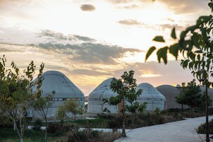 A pathway leading to large, dome-shaped buildings with a clear sky and some clouds in the background.