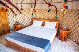 A bed in a room with a wooden headboard, a wooden nightstand, and a decorative wall.
