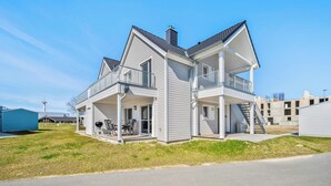 Ett tvåvåningshus med en balkong, en inglasad veranda och ett garage.