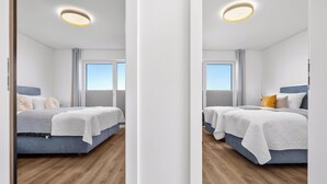 Ett modernt hotellrum med två sängar, ett stort fönster och en taklampa.