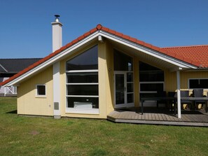 A single-story house with a red-tiled roof, large glass windows, and a wooden deck. - 4 Star Holiday Home in Grossenbrode (Grossenbrode)