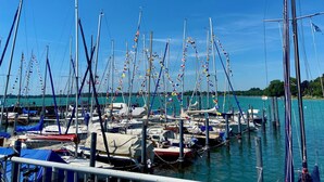 Una marina con numerosos veleros amarrados, rodeada de aguas tranquilas y cielos despejados.