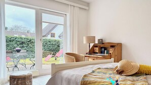 Un dormitorio con cama, escritorio, silla y vista al exterior.