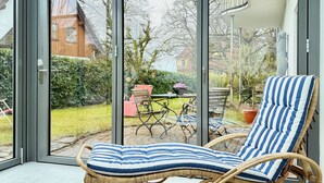 Una habitación con un gran ventanal corredero que da a un patio amoblado y vistas de una casa.