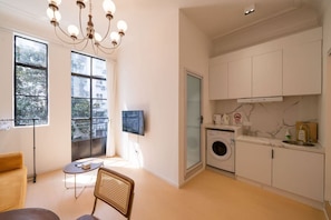 Un espacio habitable compacto con lavadora, televisor y comedor con una silla y mesa.