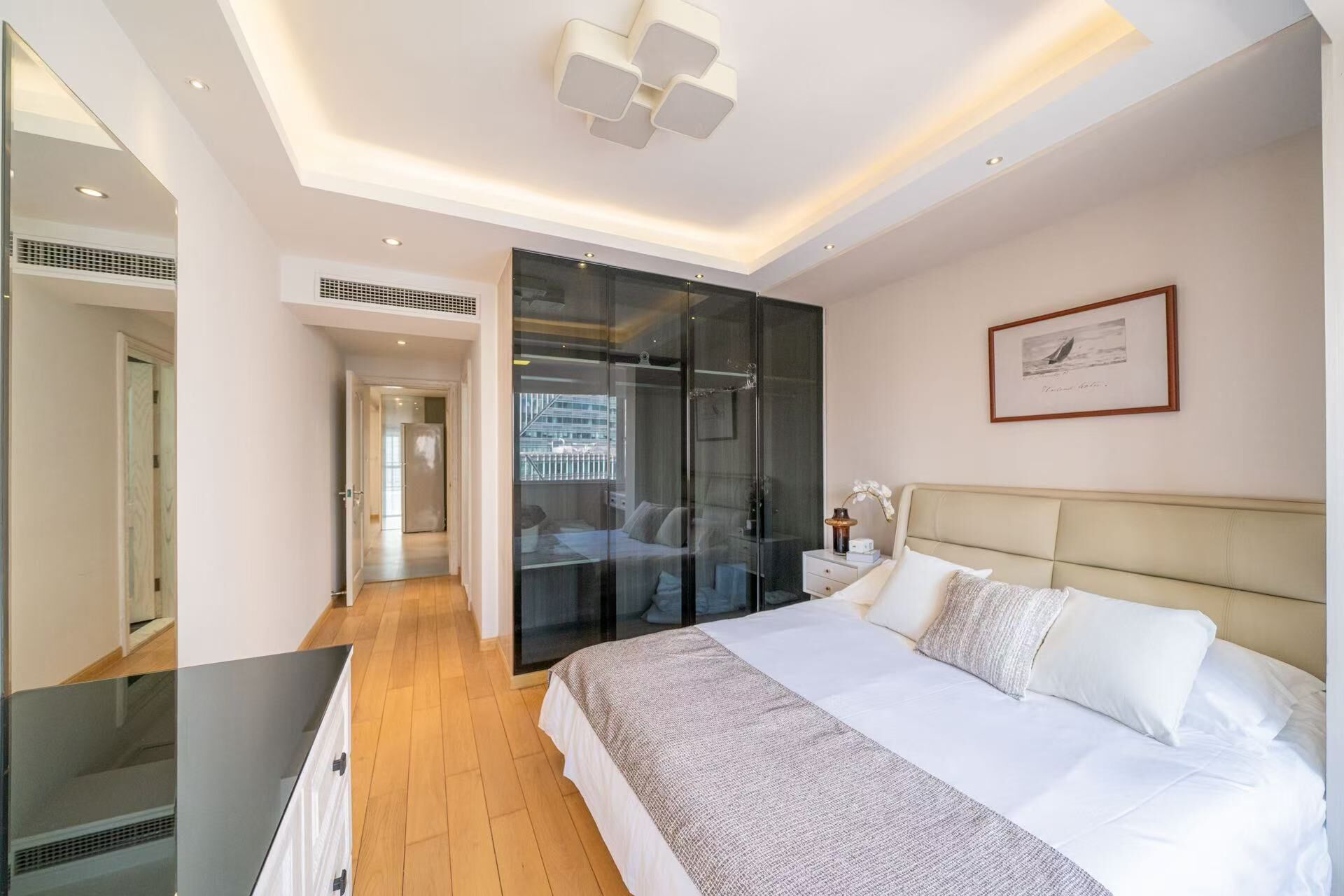 A modern bedroom with a large bed, a walk-in closet, and a view of the city.