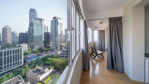 Un appartement situé dans un immeuble de grande hauteur, doté d’un balcon, de grandes fenêtres et offrant une vue sur le paysage urbain.