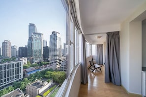 Un apartamento moderno en un edificio alto, con balcón, ventanas amplias y vista panorámica de la ciudad.
