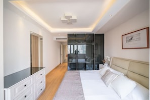 Un dormitorio con cama, mesita de noche, cómoda y un cuadro en la pared.