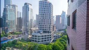 Un quartier urbain composé d’immeubles de grande hauteur, caractérisé par une architecture moderne, notamment un bâtiment remarquable dont le coin présente un design original et qui est surmonté d’une terrasse sur le toit.