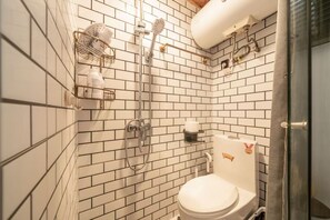 A bathroom with white tiled walls, a toilet, a shower with a handheld showerhead, and a towel rack. - Book and Bed-Nanjing West Road (Shanghai)
