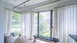 Un salon moderne avec une grande fenêtre, un canapé, un banc et un lave-linge.