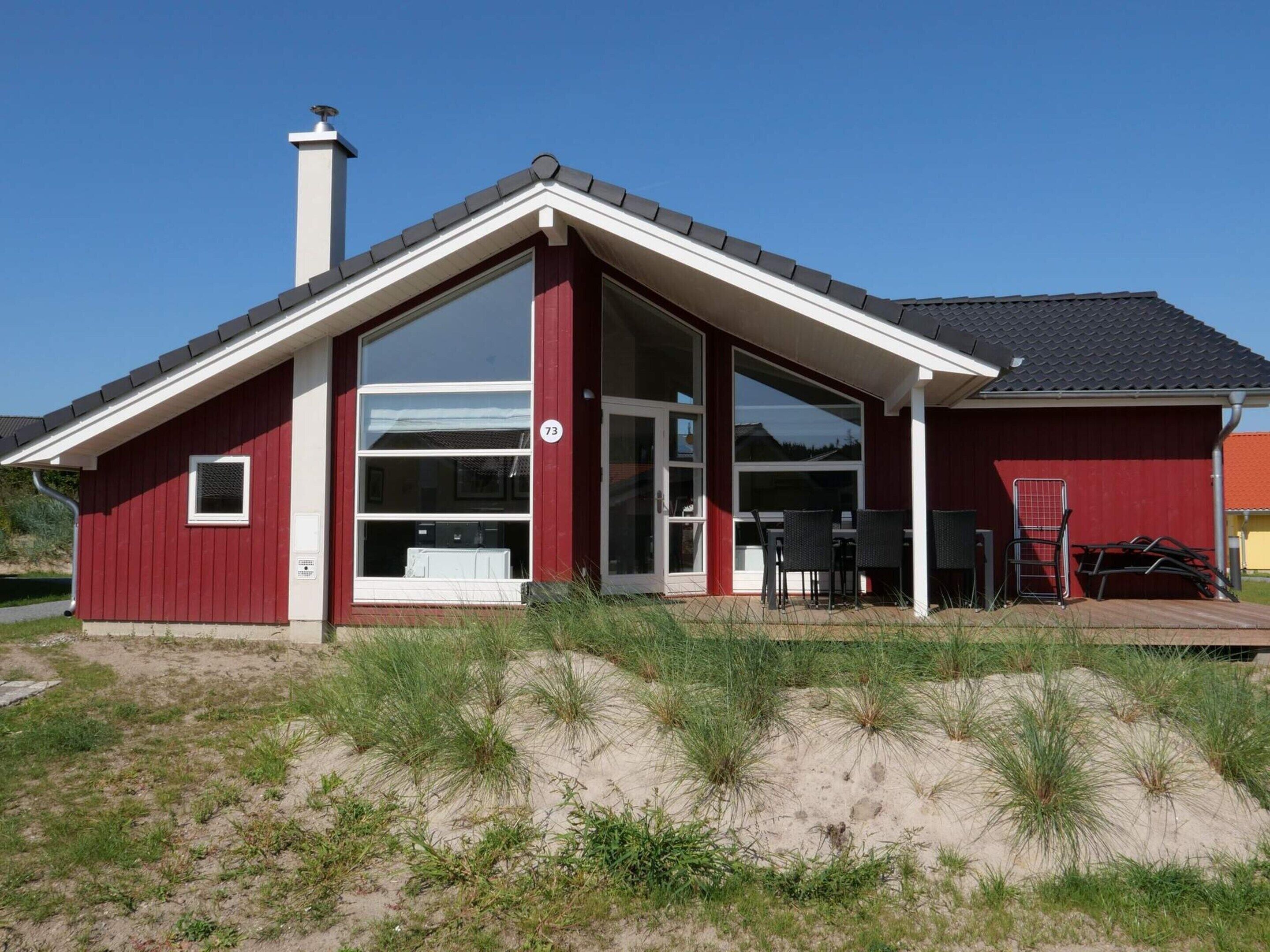 A red building with a large glass door, a chimney, and a number 73 sign.
