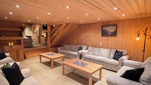 Ein gemütliches Wohnzimmer im Loft-Stil mit Holzböden, einem Kamin und einer Küche im Hintergrund.