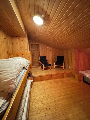 A wooden cabin room with bunk beds, two chairs, a small table, and a door. - Large cabin 27 guests with panoramic view (Buskerud)