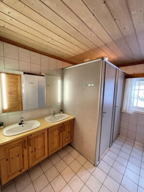 A bathroom with wooden cabinets, two sinks, a mirror, and a shower stall. - Large cabin 27 guests with panoramic view (Buskerud)