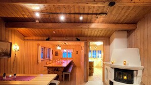 Ein Holzinterieur mit Essbereich, Kamin und Blick in einen weiteren Raum.