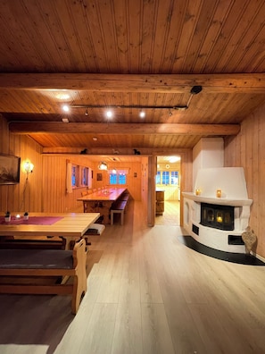 A wooden interior with a dining area, a fireplace, and a view into another room.