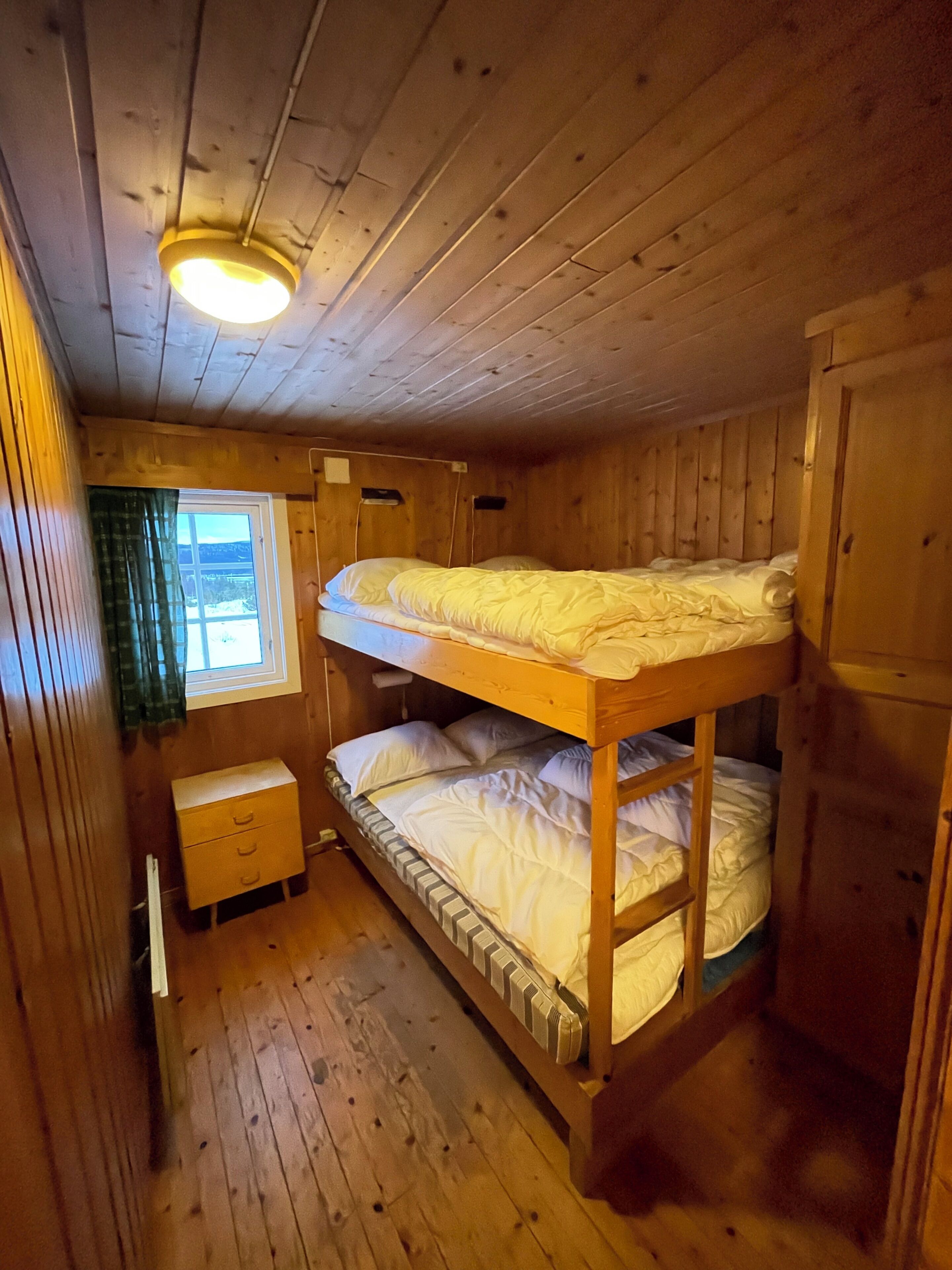 Habitación con literas, paredes de madera y ventana.