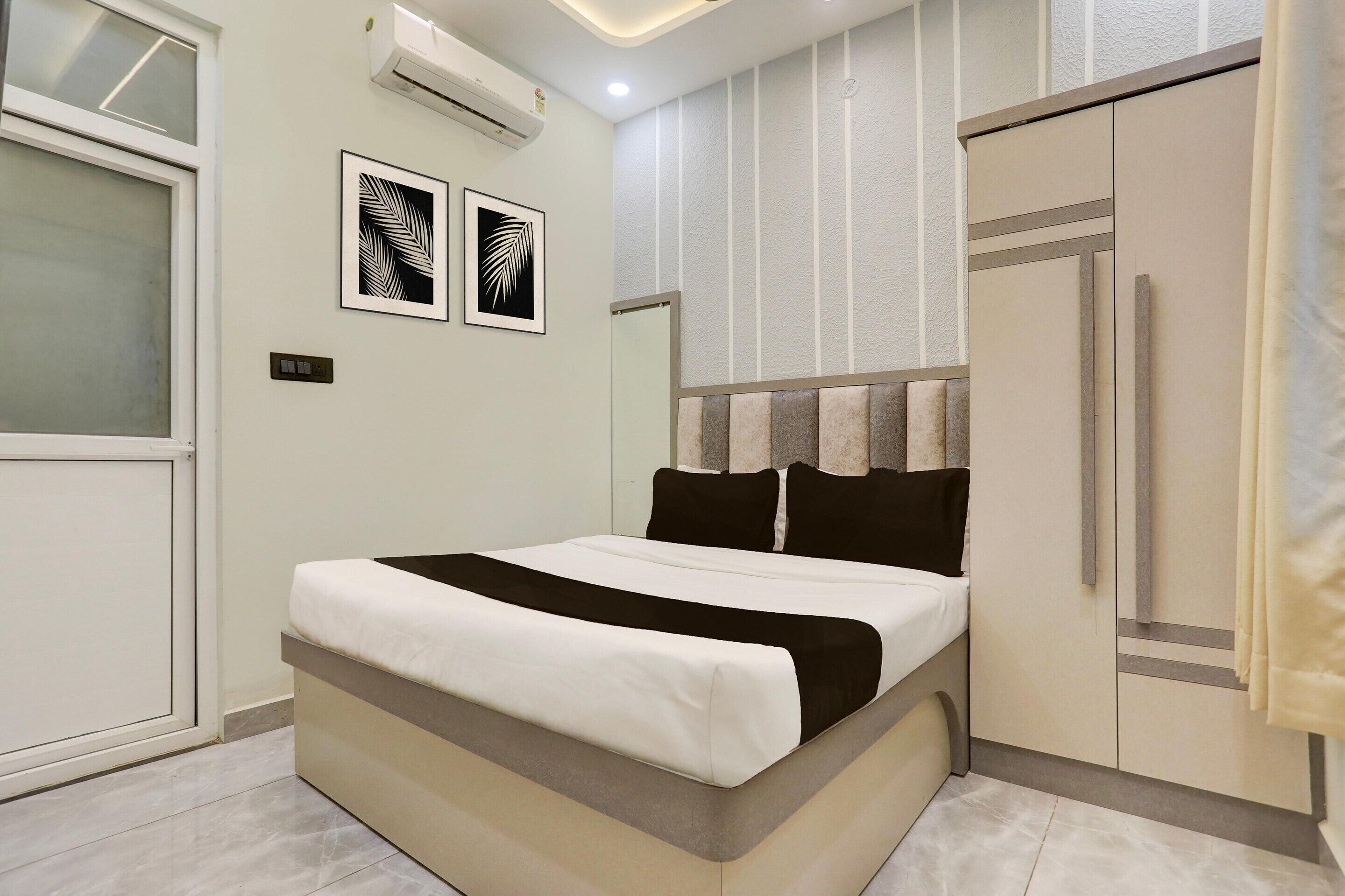 A bedroom with a bed, a wardrobe, and two wall-mounted air conditioning units.