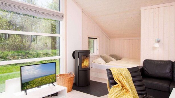 Quarto aconchegante com cama, televisão, lareira e janela com vista para o verde.
