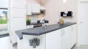 Cozinha moderna com armários brancos, bancada de granito, micro-ondas e cafeteira.