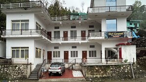 A multi-story hotel with balconies, a car parked in front, and a sign for 'Shri Ganapati Hotel & Restaurant.' - Shri Ganapati Hotel BY S4S (Ukhimath)