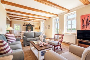 Ein Wohnzimmer mit Holzboden, einem Fernseher und einem Sofa.