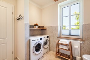 Une buanderie équipée d’un lave-linge, d’un étendoir, d’un radiateur et d’une fenêtre donnant sur un paysage agréable.