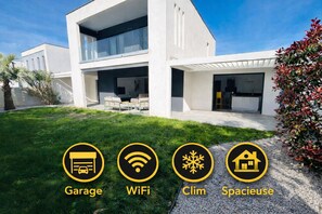 Une maison moderne à deux étages, dotée d’un garage, d’une connexion Wi-Fi, d’un espace extérieur couvert et d’un jardin.