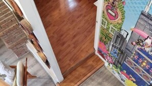 Une pièce dotée d’un plancher en bois, d’un escalier recouvert d’une moquette à motifs et d’un mur orné d’une fresque colorée.