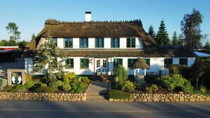 A traditional white building with a thatched roof, multiple windows, and a stone pathway leading to the entrance. - Ferienhof Birkblick "Tannengrün" (Gelting)