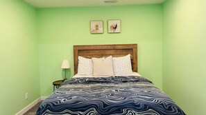 A room with a bed, a nightstand, a lamp, and two framed pictures on the wall. - Entire Basement suite (Chestermere)