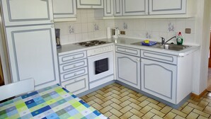 Uma cozinha com armários brancos, fogão, pia e painel de azulejos.