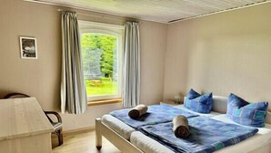 Un dormitorio con cama, cortinas, ventana, una silla y una puerta.