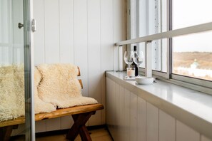A cozy seating area with a fluffy chair, a small table with a candle, wine glasses, and bottles. - Vacation apartment "FjordLoft" on the 24th floor of the Viking Tower (Schleswig)