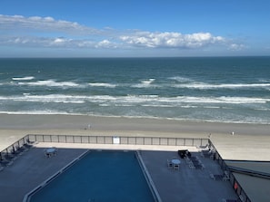 A pool area with lounge chairs and a view of the ocean. - Spectacular ocean view on no drive beach + heated rooftop saltwater pool (New Smyrna Beach)