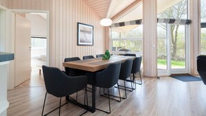 A modern interior with a wooden ceiling, a dining table with chairs, a framed picture on the wall, and large windows. - 4 Star Holiday Home in Grossenbrode (Grossenbrode)