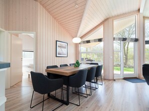A modern interior with a wooden ceiling, a dining table with chairs, a framed picture on the wall, and large windows. - 4 Star Holiday Home in Grossenbrode (Grossenbrode)