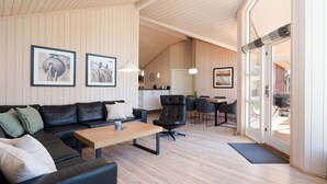 A modern living room with a sofa, coffee table, and dining area. - 4 Star Holiday Home in Grossenbrode (Grossenbrode)