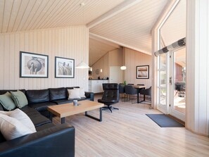 A modern living room with a sofa, coffee table, and dining area. - 4 Star Holiday Home in Grossenbrode (Grossenbrode)