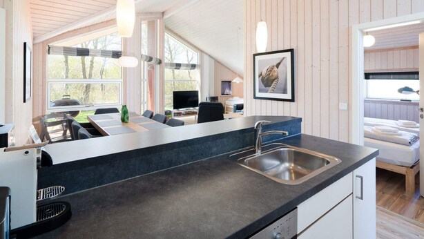A modern kitchen with a large island, a dining area, and a bedroom with a bunk bed. - 4 Star Holiday Home in Grossenbrode (Grossenbrode)