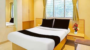 A hotel room with a bed, a nightstand, a mirror, a window with curtains, and an air conditioning unit. - Classic With Twin Bed , Pune Nagar (Pune)