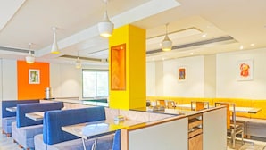 A modern restaurant with booths and tables, bright yellow accents, and artwork on the walls. - Classic With Twin Bed , Pune Nagar (Pune)