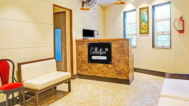 A reception area with a reception desk, a bench, a chair, a wall-mounted fire extinguisher, and a window. - Classic With Twin Bed , Pune Nagar (Pune)